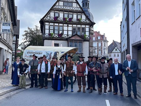 Alt-Text: Historische Schützen in traditionellen Uniformen und Gewändern mit einem Planwagen vor dem Historischen Rathaus in Höxter.