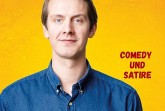 Veranstaltungsplakat zu „Jonas Greiner im Life House“ mit Porträt eines Mannes vor gelbem Hintergrund.