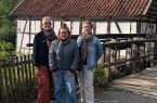 Drei Frauen stehen vor einem historischen Fachwerkgebäude mit Holzsteg und Ziegeldach.