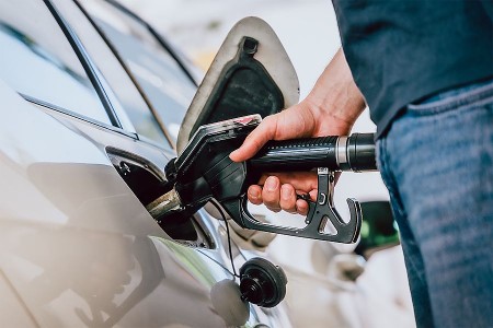 Hand hält eine Zapfpistole beim Tanken eines Autos.