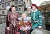 Drei Personen in historischen Renaissance-Kostümen vor Schloss Brake.