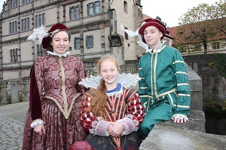 Drei Personen in historischen Renaissance-Kostümen vor Schloss Brake.