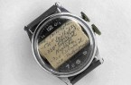 Alte Armbanduhr mit handgeschriebenem Spickzettel unter dem Uhrglas.