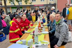 Besucherinnen und Besucher sitzen an langen Tischen beim Vlothoer Bürgerbrunch vor dem Gesundheitszentrum.