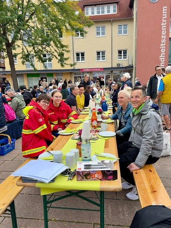 Besucherinnen und Besucher sitzen an langen Tischen beim Vlothoer Bürgerbrunch vor dem Gesundheitszentrum.