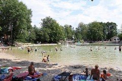 Badegäste und Familien am Ufer des Waldbads Steinhagen an einem sonnigen Sommertag.
