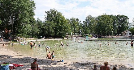 Badegäste und Familien am Ufer des Waldbads Steinhagen an einem sonnigen Sommertag.